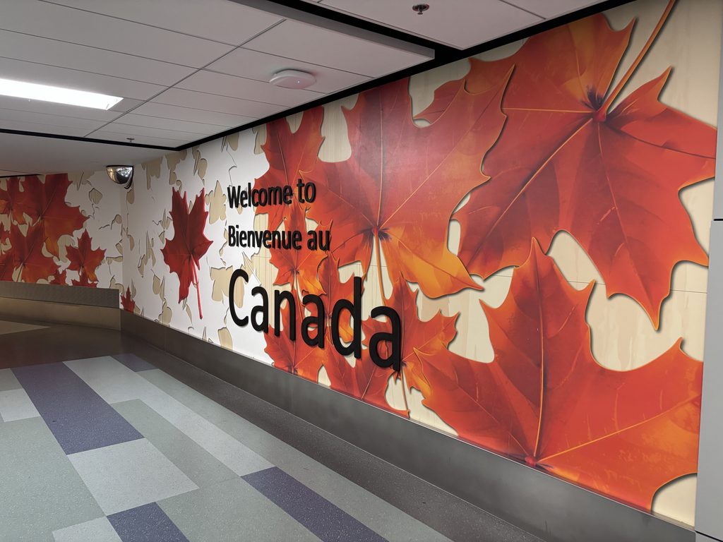 「Welcome to Canada」の文字とカエデの葉の壁。カナダに着いたんだなと実感する場所です